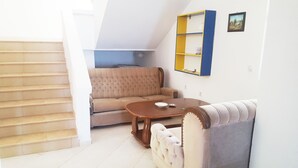 Un salon avec un canapé, une table basse et une bibliothèque.