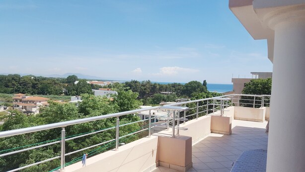 Un balcon donnant sur une zone côtière, avec vue sur des bâtiments et de la végétation.