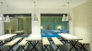 Een moderne vergaderruimte met glazen scheidingswanden, houten tafels en hangende pendellampen.
