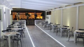 Een restaurant met een lange, open eetzal, tafels en stoelen in rijen, en een balie op de achtergrond.