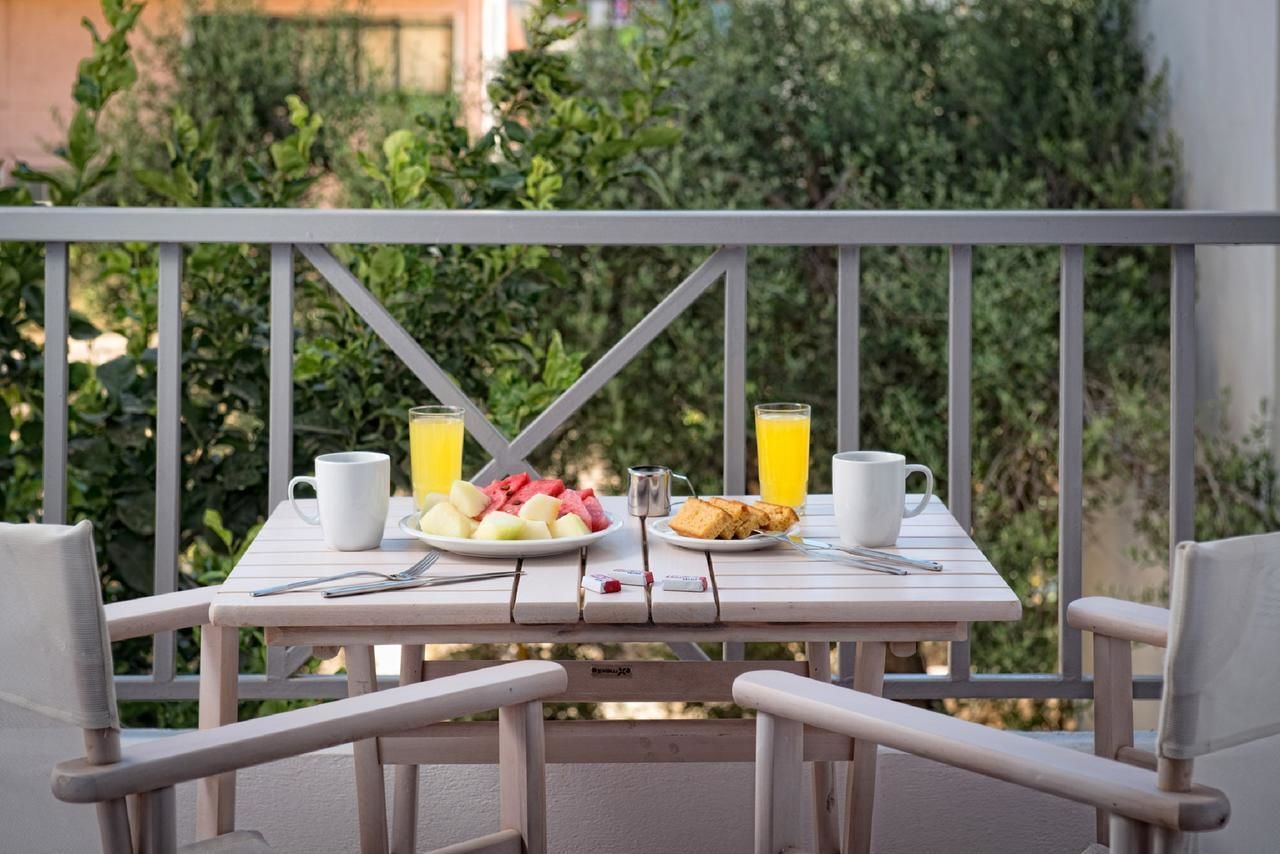 A balcony with a table set for breakfast, including plates of fruit, toast, and juice glasses.
