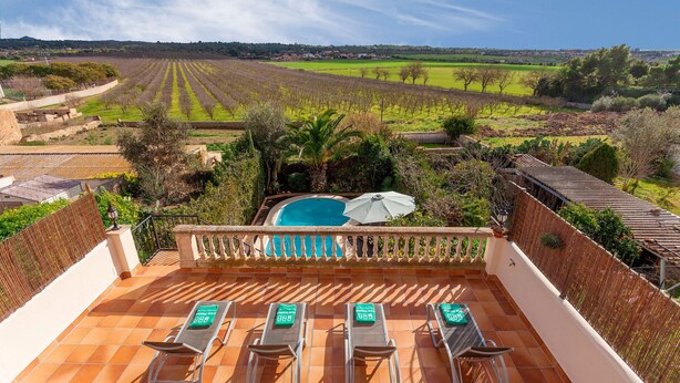 Une terrasse avec quatre chaises longues, une piscine et une vue sur des champs agricoles.