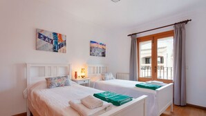 Une chambre d’hôtel avec deux lits, un balcon et des œuvres d’art aux murs.