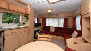 Ein kompaktes Wohnmobil-Interieur mit einer Küchenzeile, einer Essecke, einer Sitzecke und einem Fernseher.