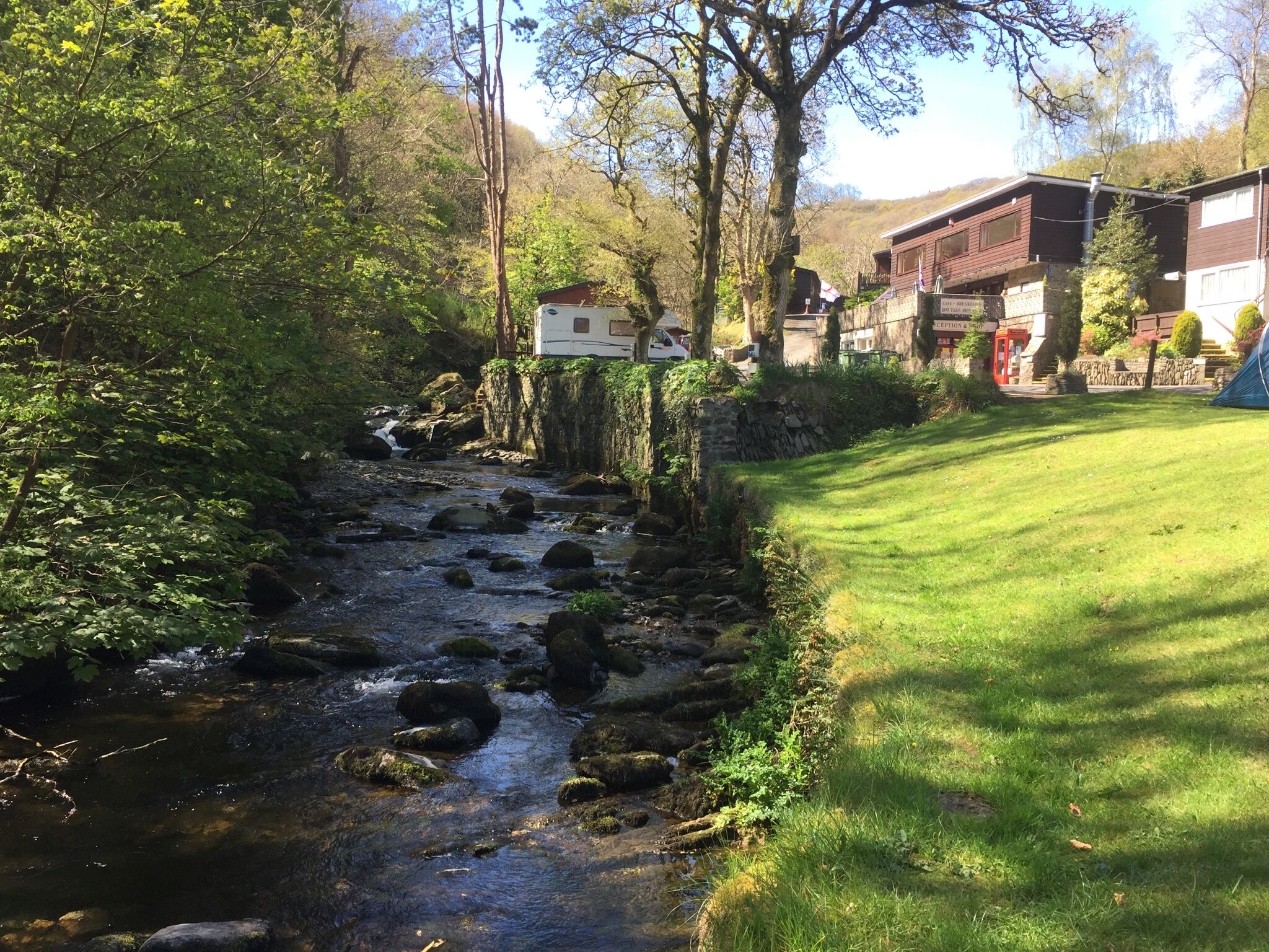 A river flowing through a wooded area with a building on the right side.