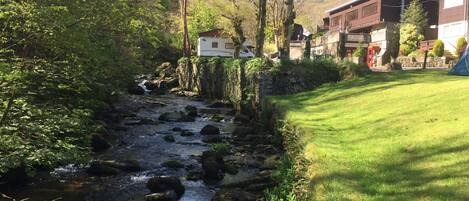 Un río fluye por una zona boscosa con un edificio a la derecha.