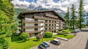 Un hôtel à plusieurs étages, doté de balcons, entouré d’une végétation luxuriante et avec des montagnes en toile de fond.