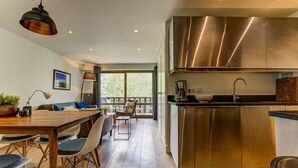 Une cuisine moderne dotée d’appareils électroménagers en acier inoxydable et d’un coin repas en bois offrant une vue sur l’extérieur.