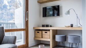 Un salon moderne avec un bureau en bois, un téléviseur et deux tabourets gris.