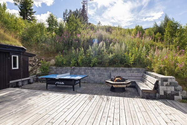 An outdoor deck with a ping pong table and a fire pit.