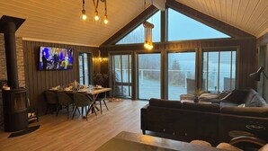 A spacious living area with a large window, a fireplace, and a television mounted on the wall.
