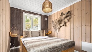 A bedroom with a wooden bed, a large window, a woven light fixture, and a fur wall.