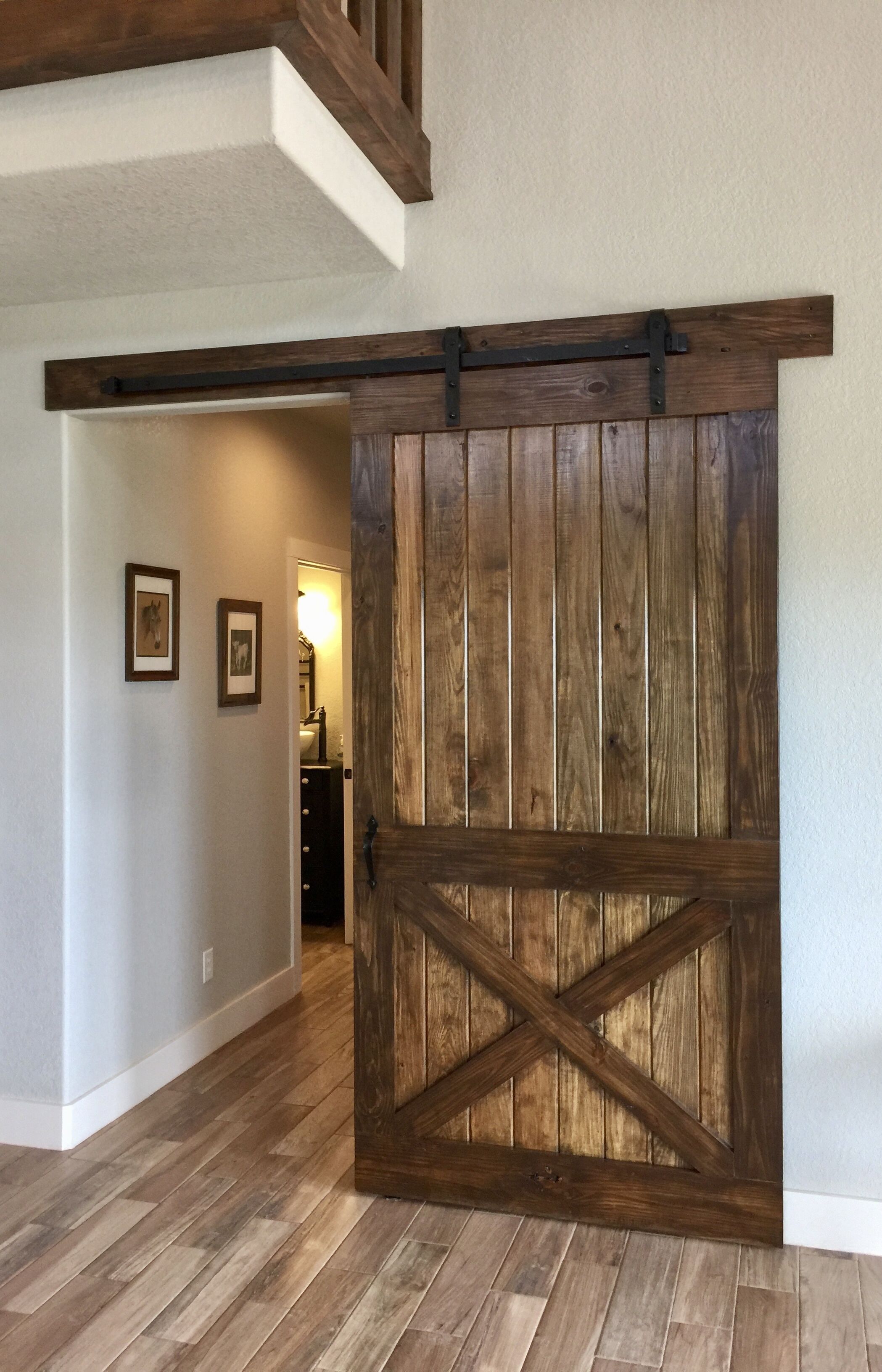 A hallway with wooden flooring and a rustic barn-style door.