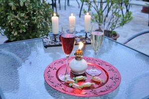 Une table avec un set de table rose, deux verres de vin, une bougie allumée et quelques bonbons.