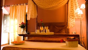 A hotel room with a bed, a bedside table with a tray of breakfast items, a vase with flowers, and a lamp. - La Casa del Canónigo - Adults Only (Huete)