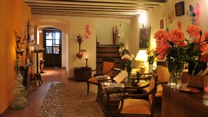 A cozy living room with a fireplace, wooden furniture, and a vase of flowers. - La Casa del Canónigo - Adults Only (Huete)