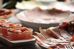 Une table sur laquelle on trouve divers aliments, notamment des tranches de viande et un saladier de fruits.