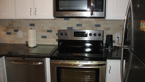 Una cocina con electrodomésticos de acero inoxidable, incluyendo un microondas, horno y refrigerador.