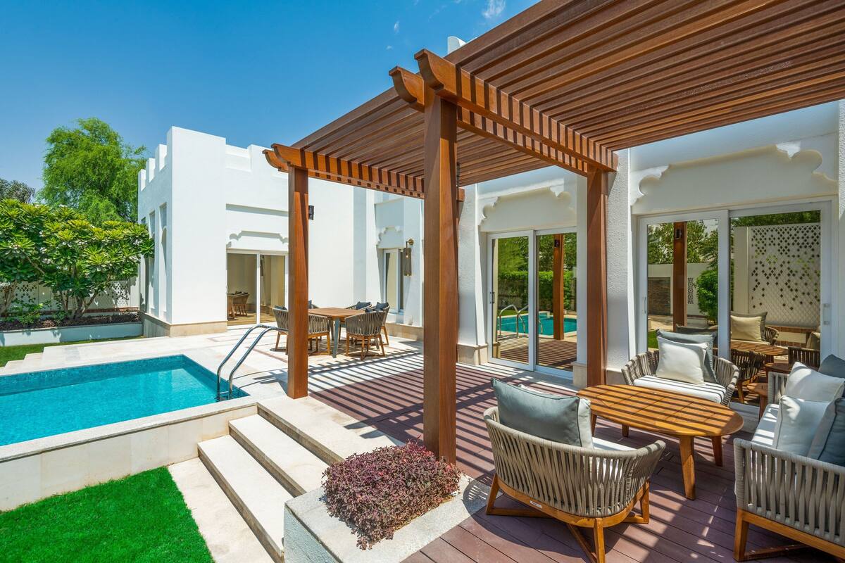 Uma área à beira da piscina com um pérgola, móveis de exterior e vista para a piscina.