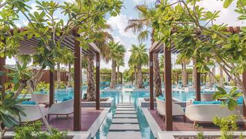 A pool area with multiple swimming pools, lounge chairs, and palm trees.