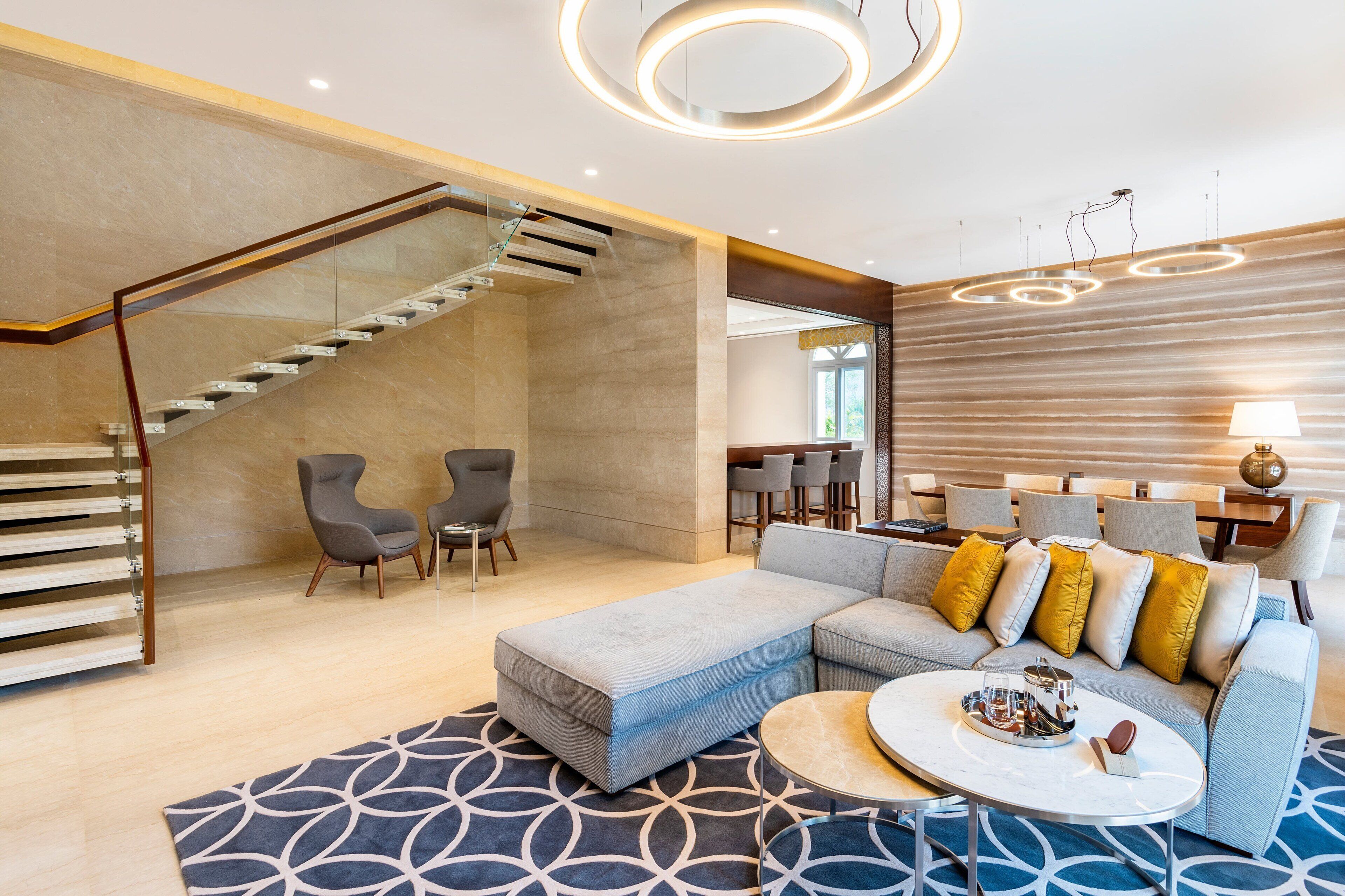 A modern living room with a staircase, a sectional sofa, and a round coffee table.