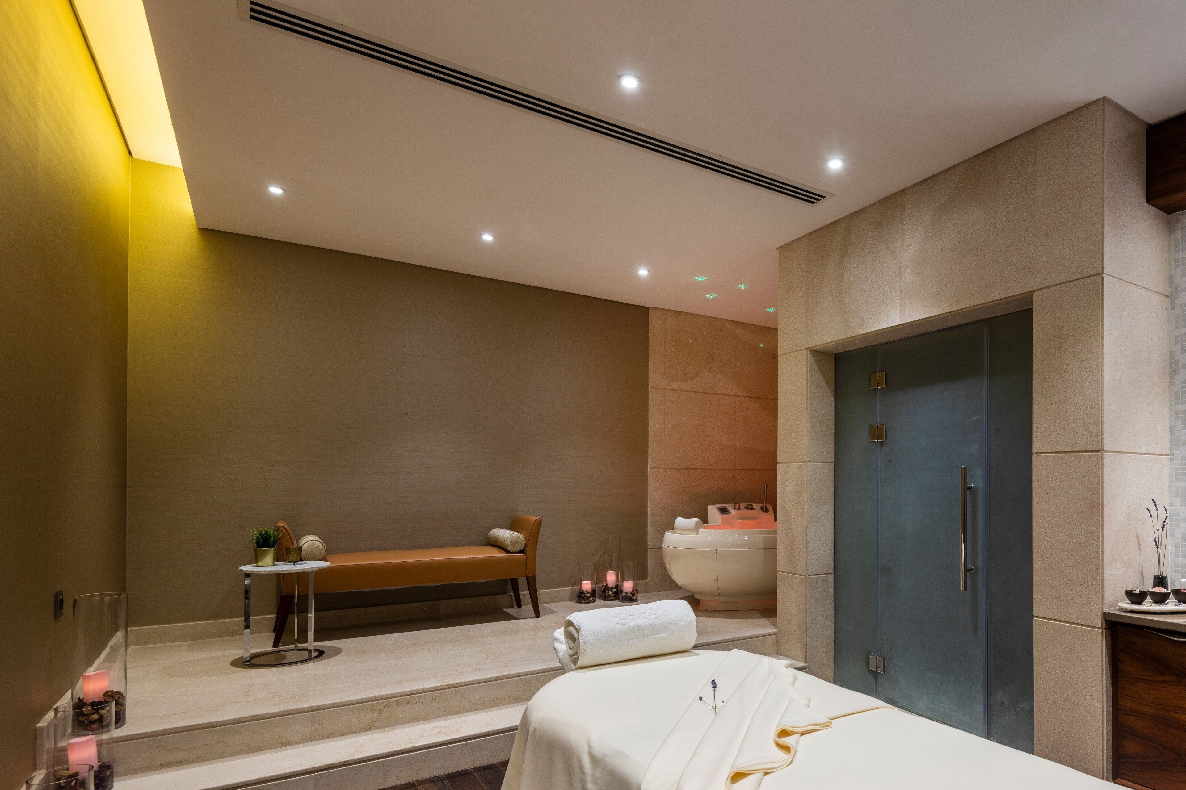 Un spa moderno con una banca, una bañera y una camilla de masaje.