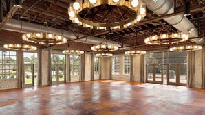 A spacious room with large windows, a polished concrete floor, and multiple circular chandeliers. - Cotton House, Cleveland, a Tribute Portfolio Hotel (Cleveland)