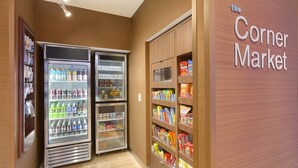 Una tienda de barrio con dispensadores de bebidas refrigeradas y estantes con productos de snacks.