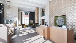 Un moderno vestíbulo de hotel con una recepción, zona de estar y vistas a la ciudad.