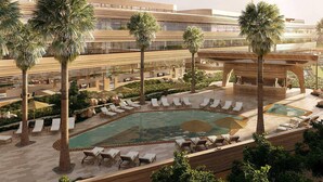 A hotel with a large outdoor pool area, palm trees, and lounge chairs. - Riyadh Diplomatic Quarter - Marriott Executive Apartments (Riyadh)