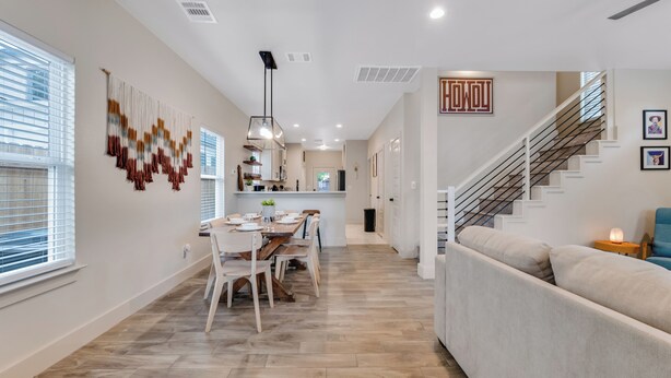 Un interior moderno con comedor, cocina, escalera y sofá.