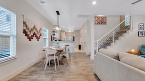 Un intérieur moderne comprenant un coin repas, une cuisine, un escalier et un canapé.