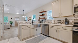 Una cocina moderna con una isla central, electrodomésticos de acero inoxidable y un revestimiento de baldosas en espiga.