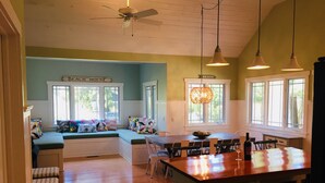 A kitchen with a wooden island, a dining table, and a built-in bench with colorful cushions. - Owls Nest Beach House - Just Steps From Our Private Beautiful Sandy Beach (Union Pier)