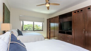 A hotel room with two beds, a ceiling fan, a TV, and a window with a view of greenery. - Penthouse via 38 Laguna by Stella Rentals (Playa del Carmen)