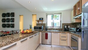 A modern kitchen with granite countertops, stainless steel appliances, and a built-in dishwasher. - Penthouse via 38 Laguna by Stella Rentals (Playa del Carmen)
