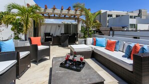 A rooftop patio with wicker furniture, a dining area, and a pergola. - Penthouse via 38 Laguna by Stella Rentals (Playa del Carmen)