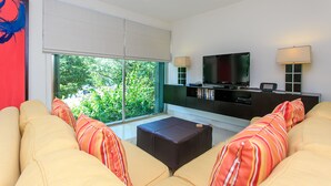 A modern living room with a large window, a flat-screen TV, a sofa, and a coffee table. - Penthouse via 38 Laguna by Stella Rentals (Playa del Carmen)