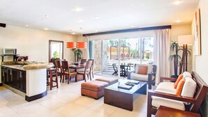 Amplia sala de estar con cocina, comedor y balcón con mobiliario exterior.