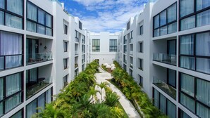 A modern building with multiple floors, large windows, and a central courtyard with greenery. - Penthouse A-Nah by Stella Rentals (Playa del Carmen)