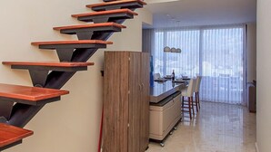 A modern staircase with wooden steps and metal railings, leading to a dining area with a view of the sky through large windows. - Penthouse A-Nah by Stella Rentals (Playa del Carmen)