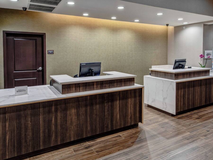 Zona de recepción con un mostrador de madera, una barra de mármol y un cartel con el nombre del hotel.