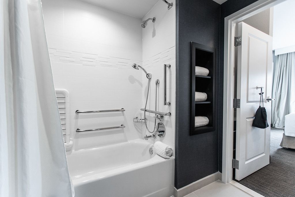 A modern bathroom with a bathtub, shower, and towel rack.