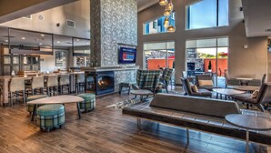 A spacious lobby with a fireplace, seating areas, and a bar. - Residence Inn by Marriott Tulsa Midtown (Tulsa)