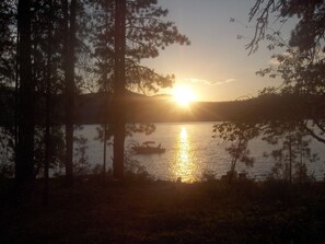 Un coucher de soleil sur un lac bordé d’arbres.