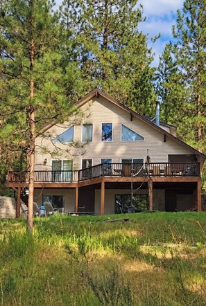 A two-story house with a balcony, surrounded by trees.