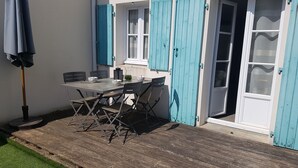 An outdoor patio with a table and chairs, a small table with a pitcher and bowls, and a wooden deck. - Vacation atmosphere - House - Swimming pool - Île de Ré (La Flotte en Ré)