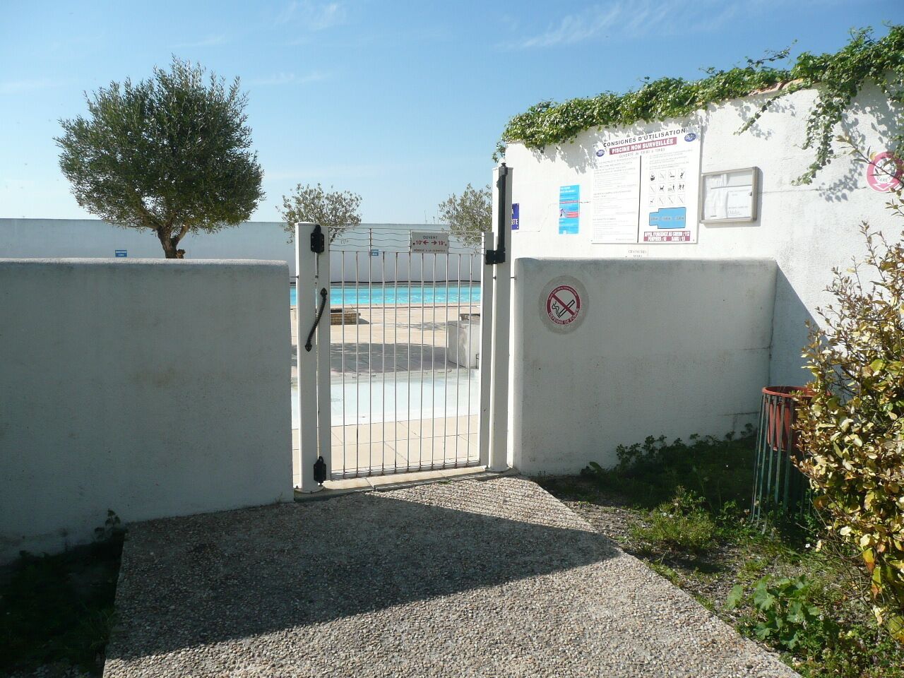 A gated entrance to a building with a pool visible through the gate.