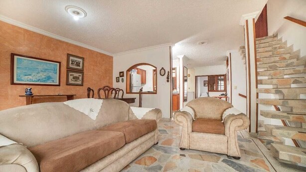 Uma sala de estar com piso estampado em pedra, dois sofás, uma lareira e uma escada.