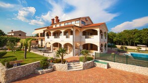 A large, two-story villa with a stone facade, multiple balconies, and a swimming pool. - Beautiful modern villa in a small village near the sea (Trget)